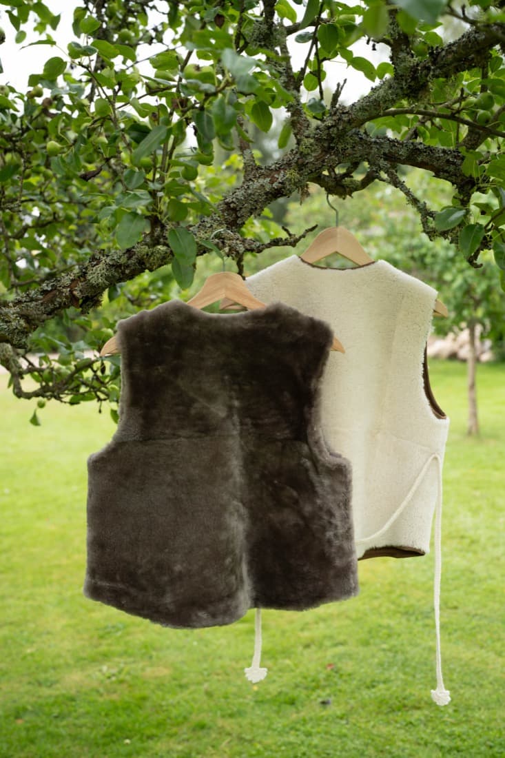 Handmade grey and cream shearling vest hanging outdoors in a Swedish garden