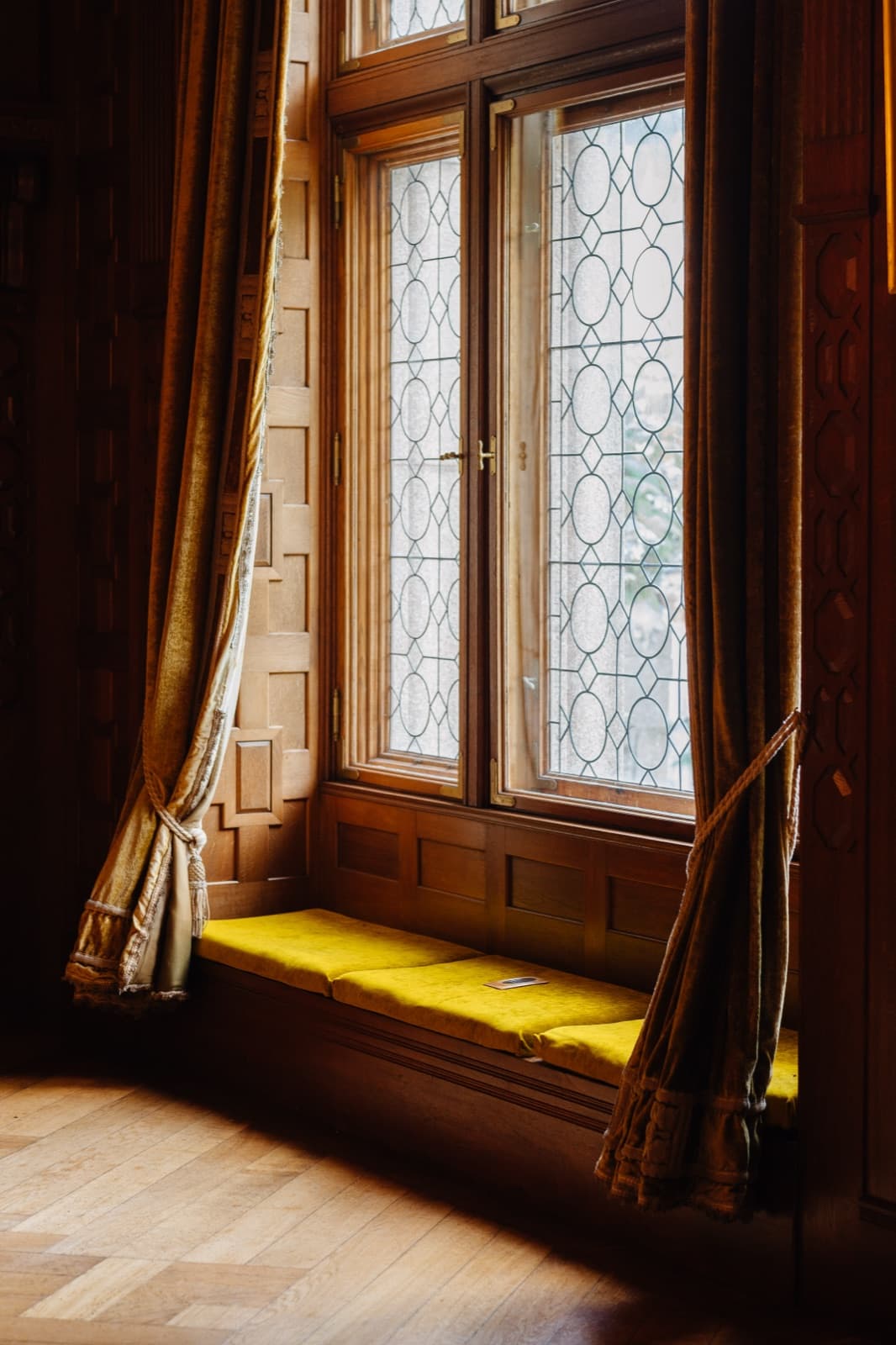 A velvet window seat with a yellow cushion below leaded windows at Tjolöholm Castle